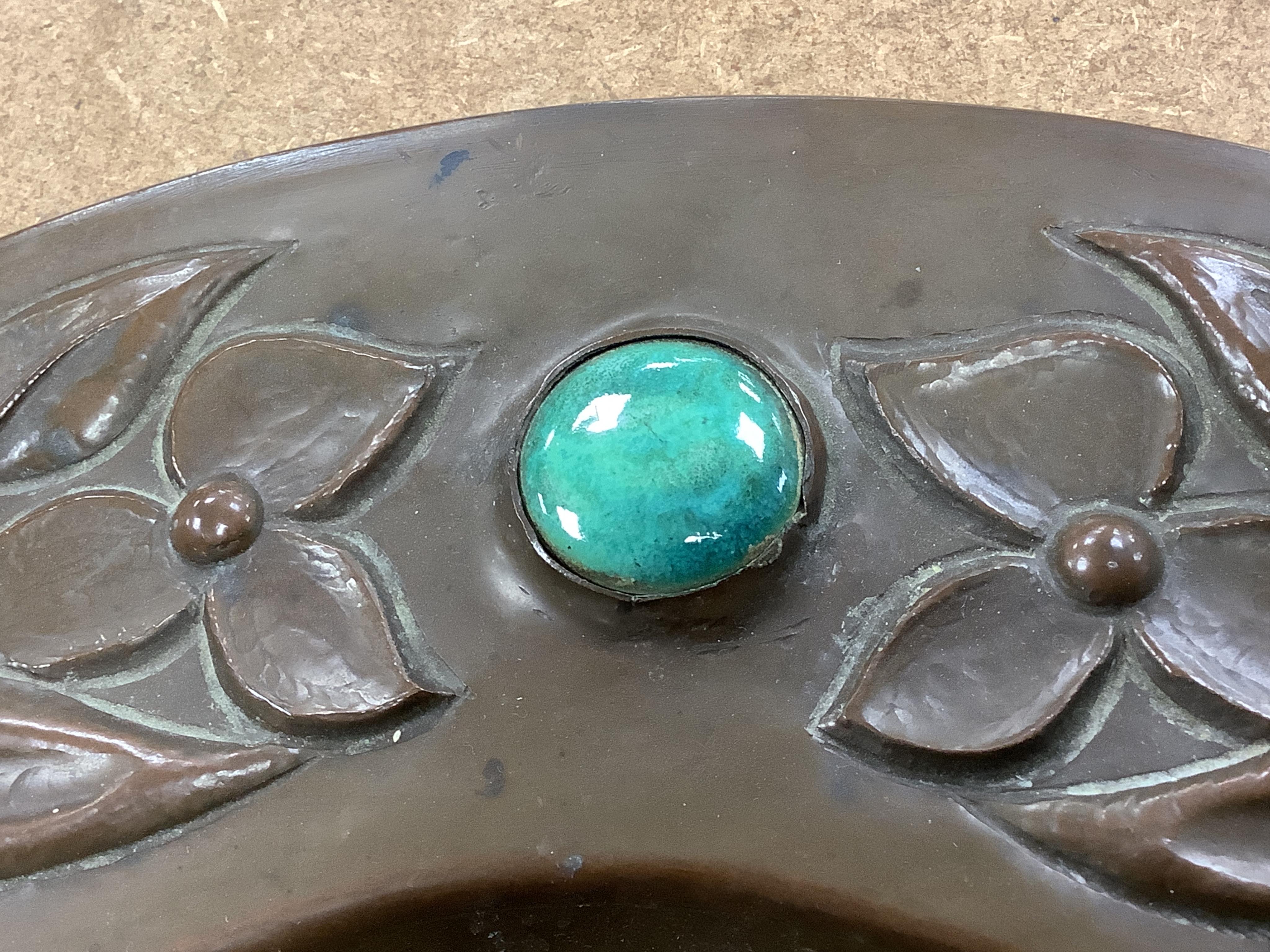 An Arts and Crafts embossed copper dish, in the manner of John Pearson, inlaid with Ruskin cabochons, unsigned, 32cm in diameter